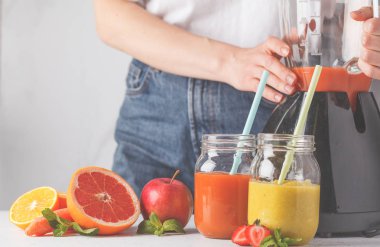 Kadın çok renkli yaz meyve suları ya da iki yüzlü cam kavanoz ve malzemelerin üzerine beyaz masa yemek.