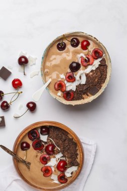 Çikolata - Hindistan cevizi ve muz beyaz arka planda, üstten görünüm ile kiraz smoothie kase. Sağlıklı vegan gıda kavramı. Çiğ vegan yaşam tarzı.