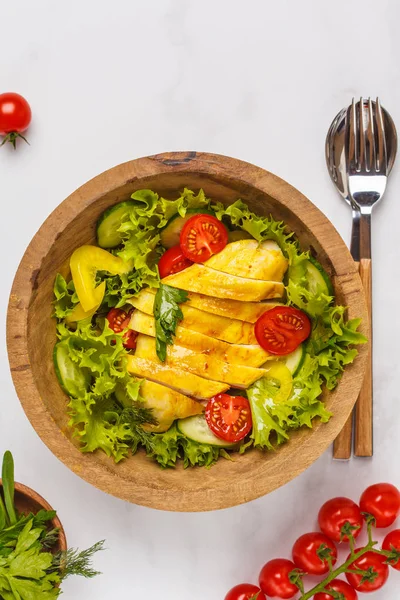 Beyaz bir arka planda, kopya alanı, üstten görünüm ahşap bir kasede sebzeli ızgara tavuk salata. Sağlıklı ve dengeli beslenme kavramı.