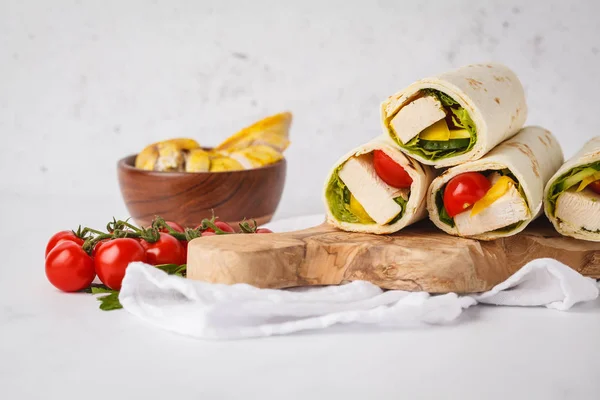 Grilled burrito wraps with chicken and vegetables (fajitas, pita bread, shawarma) on wooden board