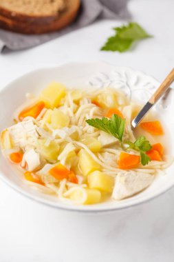 Tavuk çorbası erişte ve sebze beyaz tabak, beyaz arka plan ile.