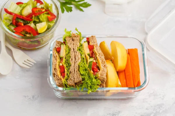 Healthy meal prep glass containers with cheese vegetables sandwiches and vegetable salad overhead shot with copy space