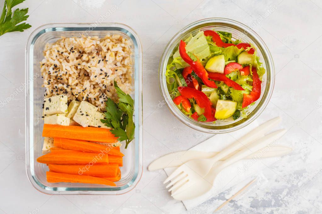 Healthy meal prep containers with brown rice, tofu and vegetable salad overhead shot with copy space. Healthy vegan food concept.