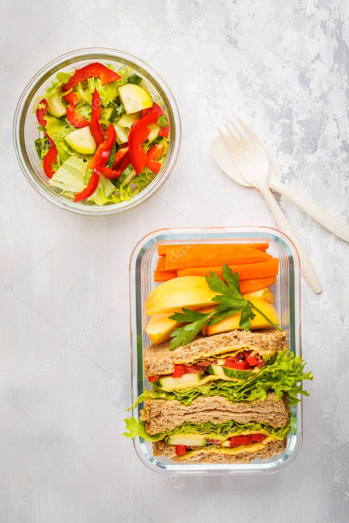 Healthy meal prep glass containers with cheese vegetables sandwiches and vegetable salad overhead shot with copy space