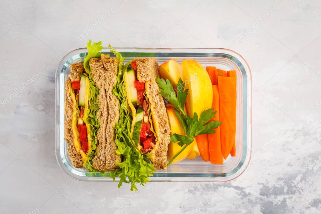 Healthy meal prep glass container with cheese vegetables sandwiches and vegetable salad overhead shot with copy space
