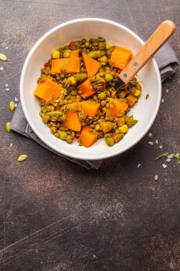 Mercimek ile tatlı patates yahni karanlık bir arka plan üzerinde beyaz bir kase. Sağlıklı vegan gıda kavramı.