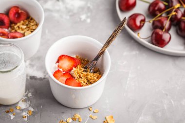 Ev yapımı granola Hindistan cevizi yoğurt ve küçük beyaz kase çilek ile. Sağlıklı gıda kavramı.