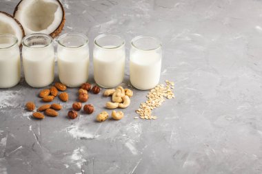 Vegan alternatif fındık süt gri bir arka plan üzerinde cam şişelerde. Sağlıklı vegan gıda kavramı.