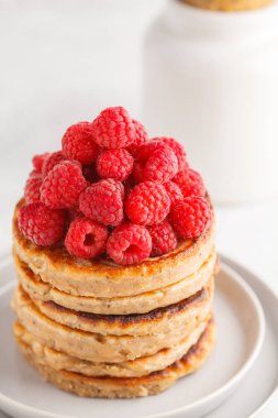 Ahududu ve beyaz tabak, beyaz arka plan üzerinde chia tohum ile Vegan krep. Sağlıklı vegan gıda kavramı.