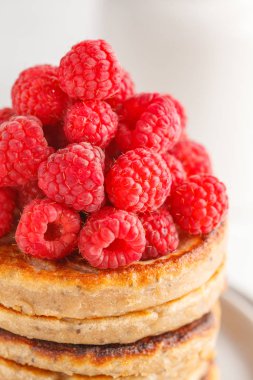 Ahududu ve beyaz tabak, beyaz arka plan üzerinde chia tohum ile Vegan krep. Sağlıklı vegan gıda kavramı.