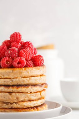 Ahududu ve beyaz tabak, beyaz arka plan üzerinde chia tohum ile Vegan krep. Sağlıklı vegan gıda kavramı.