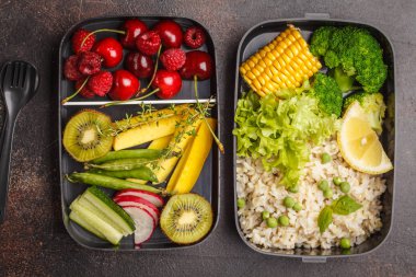 Healthy meal prep containers with brown rice, broccoli, vegetables, fruits and berries overhead shot with copy space, dark backrground, top view clipart