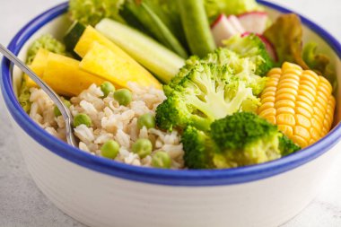 Pirinç ve sebze ile sağlıklı öğle yemeği. Vegan Buda kaseyle kahverengi pirinç, brokoli ve beyaz bir arka plan beyaz bir tabakta sebze.