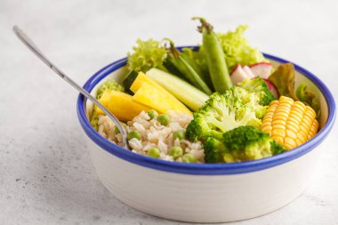 Pirinç ve sebze ile sağlıklı öğle yemeği. Vegan Buda kaseyle kahverengi pirinç, brokoli ve beyaz bir arka plan beyaz bir tabakta sebze.