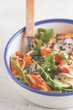 Gökkuşağı vegan salata roka, tatlı patates, turp, tahin sosu ve salatalık, beyaz arka plan ile. Sağlıklı vegan gıda kavramı.