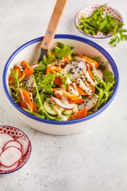 Gökkuşağı vegan salata roka, tatlı patates, turp, tahin sosu ve salatalık, beyaz arka plan ile. Sağlıklı vegan gıda kavramı.