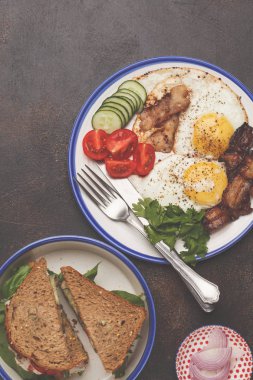 Pastırma ve et, peynir ve sebze koyu arka plan, üstten görünüm üzerinde bir sandviçle ile kızarmış yumurta. Lezzetli kahvaltı.