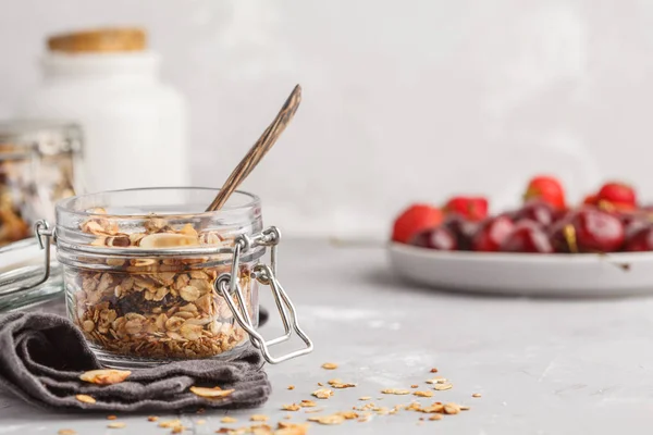 Homemade oat granola in glass jars with cherry and milk. Healthy food concept.