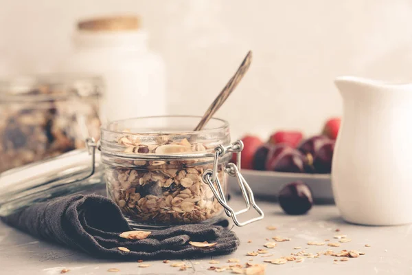 Homemade oat granola in glass jars with cherry and milk. Healthy food concept.
