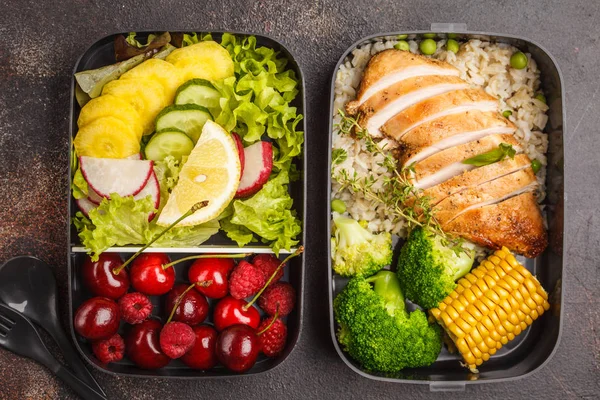 Sağlıklı yemek kapları ile meyve, çilek, pilav ve sebze ızgara tavuk ile hazırlayın. Paket servisi olan restoran gıda jn koyu arka plan, üstten görünüm