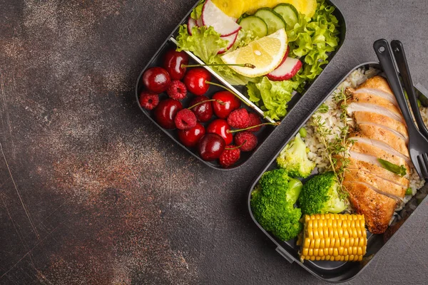 Sağlıklı yemek kapları ile meyve, çilek, pilav ve sebze ızgara tavuk ile hazırlayın. Paket servisi olan restoran gıda jn koyu arka plan, üstten görünüm