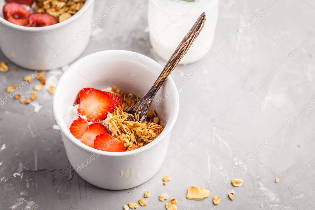 Homemade granola with coconut yogurt and berries in small white bowls. Healthy food concept.