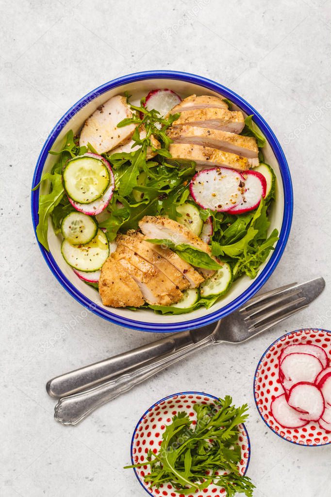 Fried chicken fillet and fresh vegetable salad of radish, arugula and cucumber. Grilled chicken breast salad. Healthy food. Food flat lay, top view, copy space, white background.