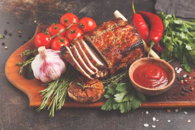 Ahşap bir masa, koyu arka plan üzerinde kekik, biberiye, sarımsak ve domates soslu kızarmış domuz eti