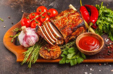 Ahşap bir masa, koyu arka plan üzerinde kekik, biberiye, sarımsak ve domates soslu kızarmış domuz eti