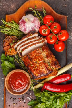 Ahşap bir masa, koyu arka plan üzerinde kekik, biberiye, sarımsak ve domates soslu kızarmış domuz eti