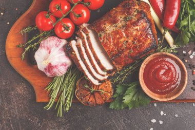 Ahşap bir masa, koyu arka plan üzerinde kekik, biberiye, sarımsak ve domates soslu kızarmış domuz eti