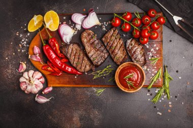 Izgara Dana biftek ile baharat ve sebzeler ahşap kesme tahtası, koyu arka plan, üstten görünüm