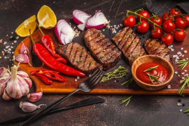 Izgara Dana biftek ile baharat ve sebzeler ahşap kesme tahtası, koyu arka plan, üstten görünüm