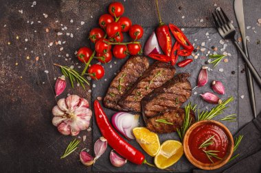 Baharatlar ve sebzeler kayrak tahta, koyu arka plan üzerinde ızgara sığır eti biftek