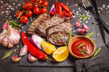 Baharatlar ve sebzeler kayrak tahta, koyu arka plan üzerinde ızgara sığır eti biftek