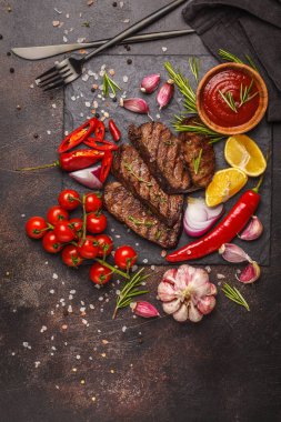 Baharatlar ve sebzeler kayrak tahta, koyu arka plan üzerinde ızgara sığır eti biftek