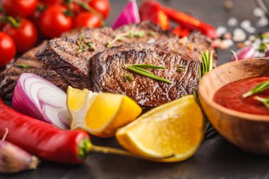 Baharatlar ve sebzeler kayrak tahta, koyu arka plan üzerinde ızgara sığır eti biftek