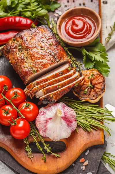 stock image Baked pork with thyme, rosemary, garlic and tomato sauce on a wooden board, light background, copy space.