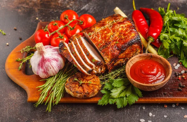 Ahşap bir masa, koyu arka plan üzerinde kekik, biberiye, sarımsak ve domates soslu kızarmış domuz eti