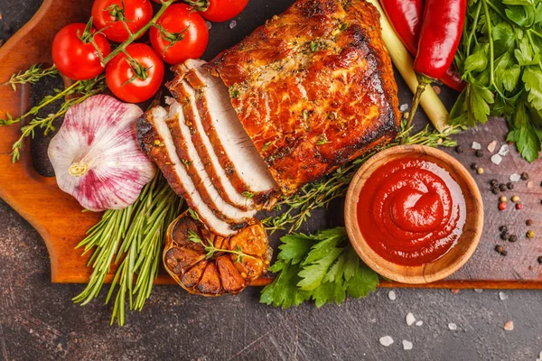 Ahşap bir masa, koyu arka plan üzerinde kekik, biberiye, sarımsak ve domates soslu kızarmış domuz eti