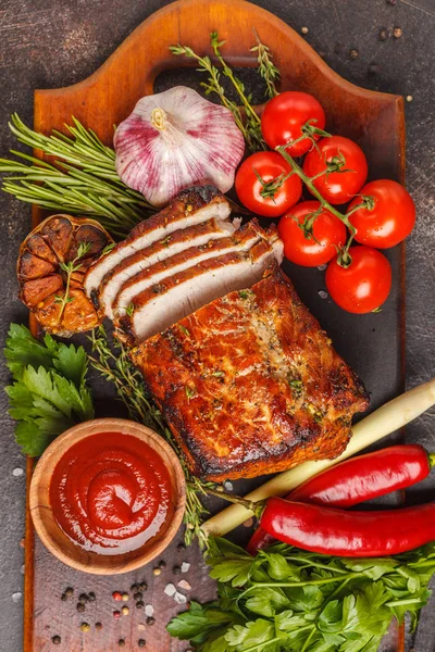 Ahşap bir masa, koyu arka plan üzerinde kekik, biberiye, sarımsak ve domates soslu kızarmış domuz eti