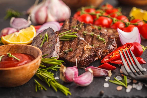 Baharatlar ve sebzeler kayrak tahta, koyu arka plan üzerinde ızgara sığır eti biftek
