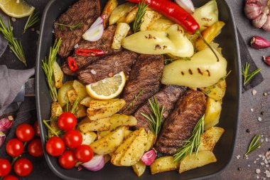 Fırında patates ve sebzeler bir pan ızgara, koyu arka plan, üstten görünüm ile sığır eti biftek ızgara.