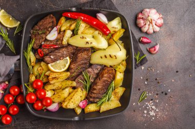 Fırında patates ve sebzeler bir pan ızgara, koyu arka plan, üstten görünüm ile sığır eti biftek ızgara.