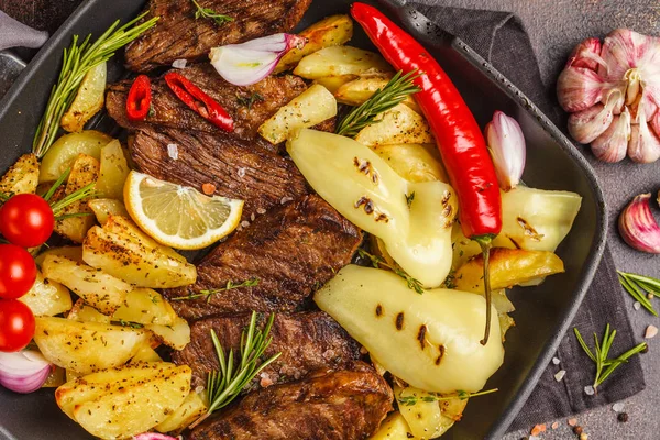 Fırında patates ve sebzeler bir pan ızgara, koyu arka plan, üstten görünüm ile sığır eti biftek ızgara.