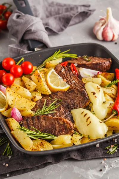 Fırında patates ve sebze pan kızartma, gri arka planda ile sığır eti biftek ızgara.