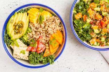Vegan sağlıklı gökkuşağı salata, quinoa, tofu, avokado ve kale, üstten görünüm, beyaz arka plan ile Buda kase.