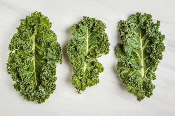 Leaves of kale on a white background. Top view, copy space. Healthy food background, clean eating concept.