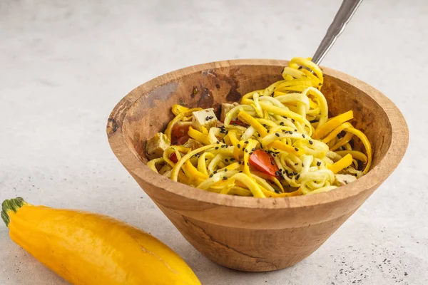 Raw vegan zucchini noodles with tofu and tomatoes in a wooden bowl. Healthy raw vegan food concept.