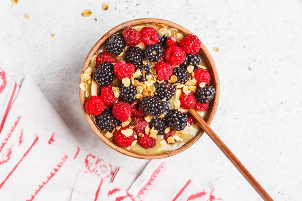 Healthy breakfast. Smoothie bowl with berries. Vegan avocado banana ice cream with berries and granola in a wooden bowl, top view.